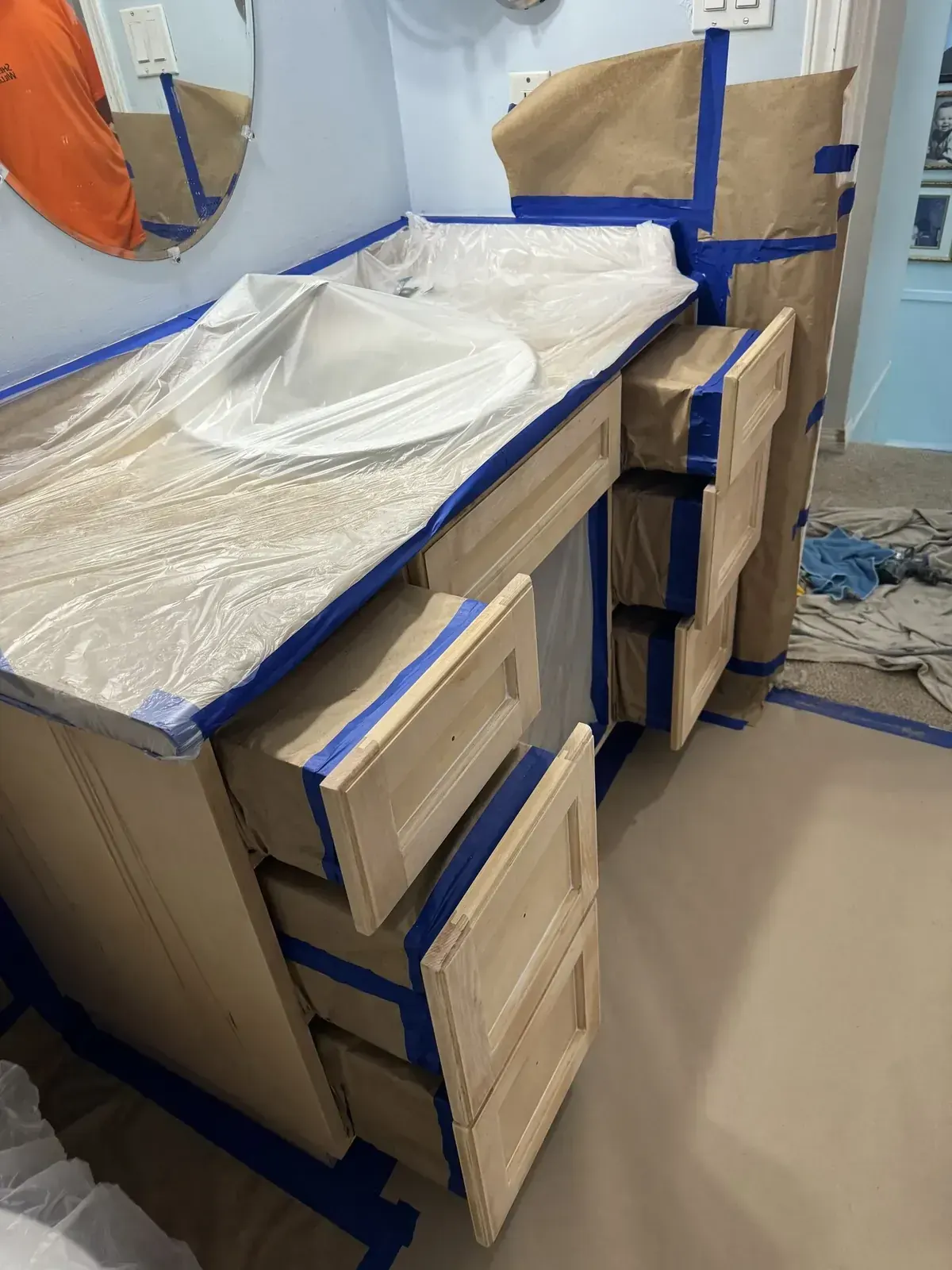 Cabinet refinishing in progress with surfaces masked